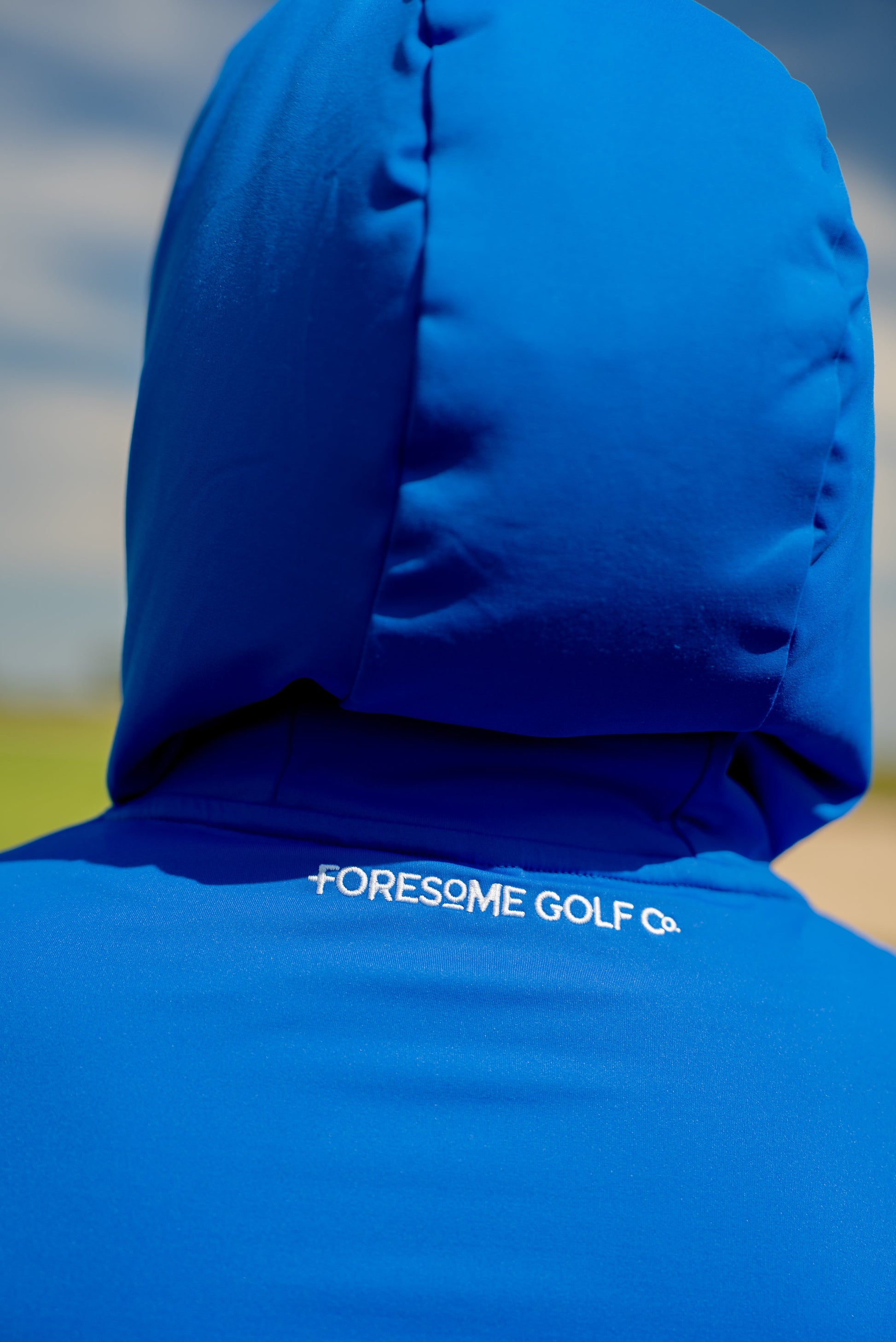 Close-up detail of hoodie’s upper back showing embroidered “Foresome Golf Co.” stitching at the neckline—subtle branding with premium finish.